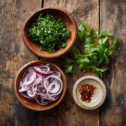 Chopped fresh parsley, sliced red onion, crushed red pepper flakes, and parsley leaves in small bowls on a wooden table.