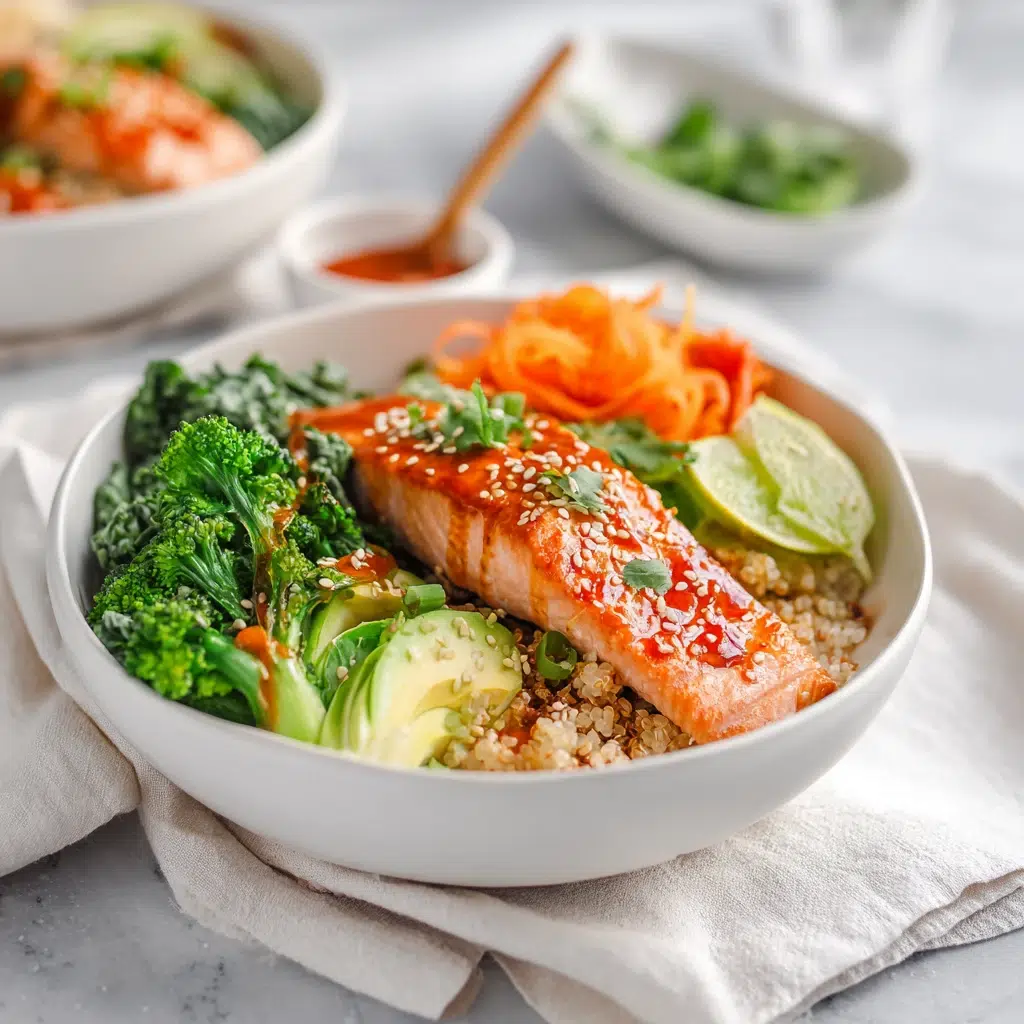 A bowl of honey sriracha glazed salmon chunks over rice with sliced avocado, cucumber, and sesame seeds.